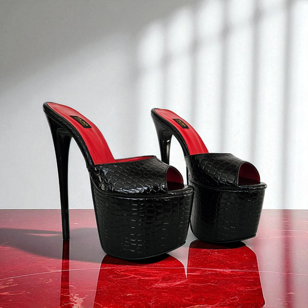 Black high-heeled platform shoes with red interior on a reflective surface.