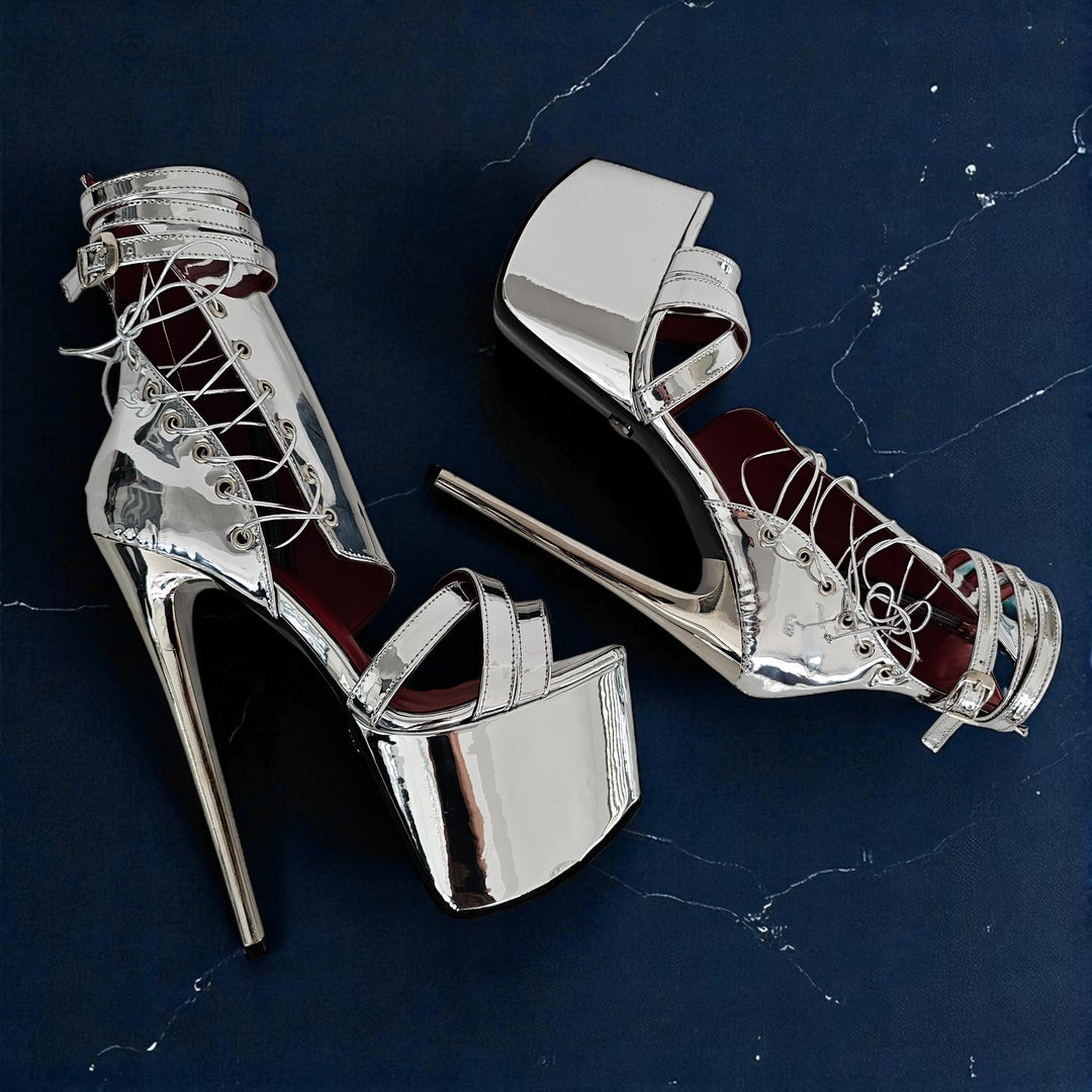 Silver high-heeled shoes with red interior on a dark blue marble surface