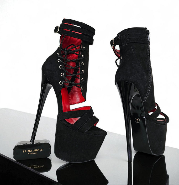 Black high-heeled shoes with red interior on a reflective surface, branded 'Taina Shoes'.