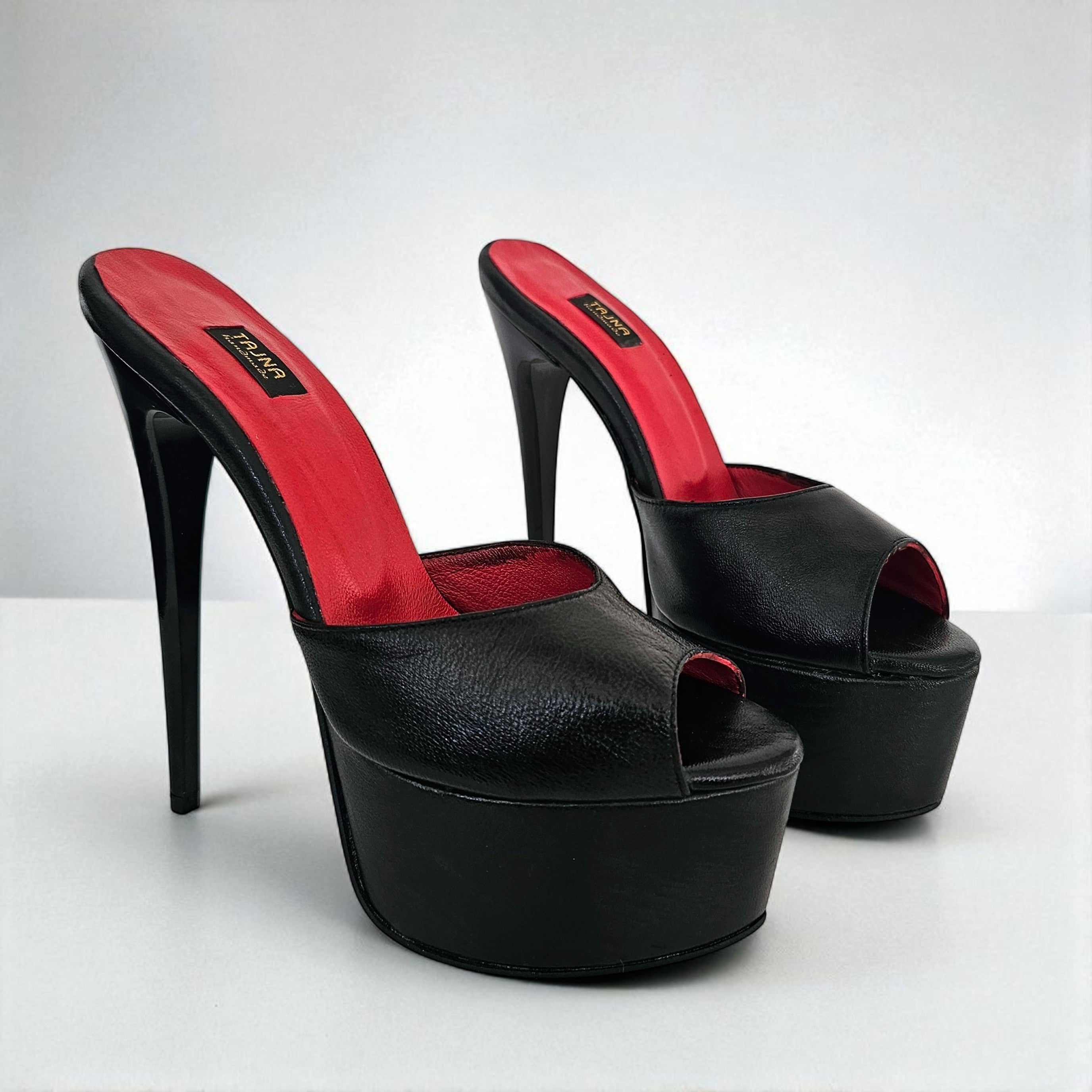 Black high-heeled platform shoes with red interior on a white background