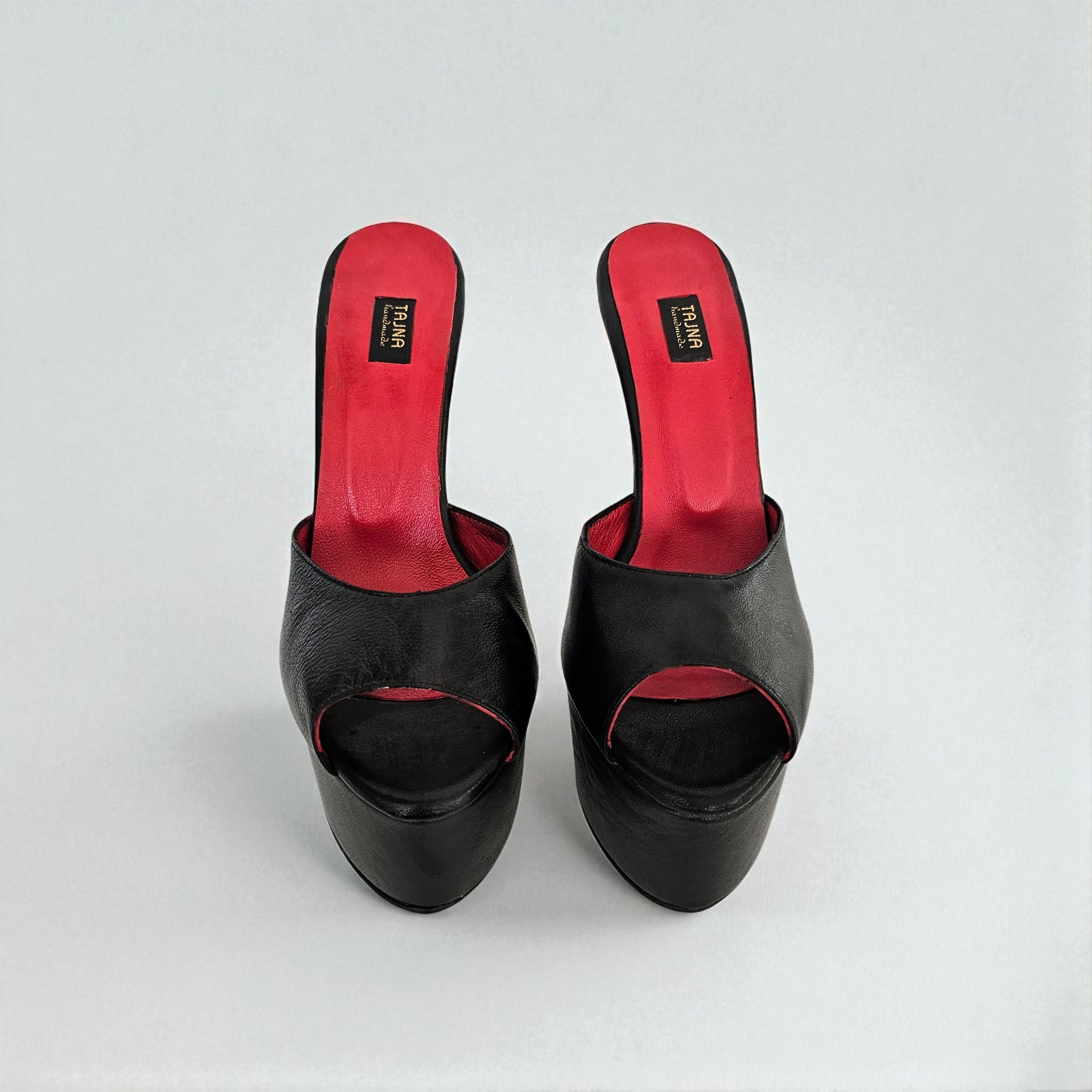 Black high-heeled shoes with red interior on a white background