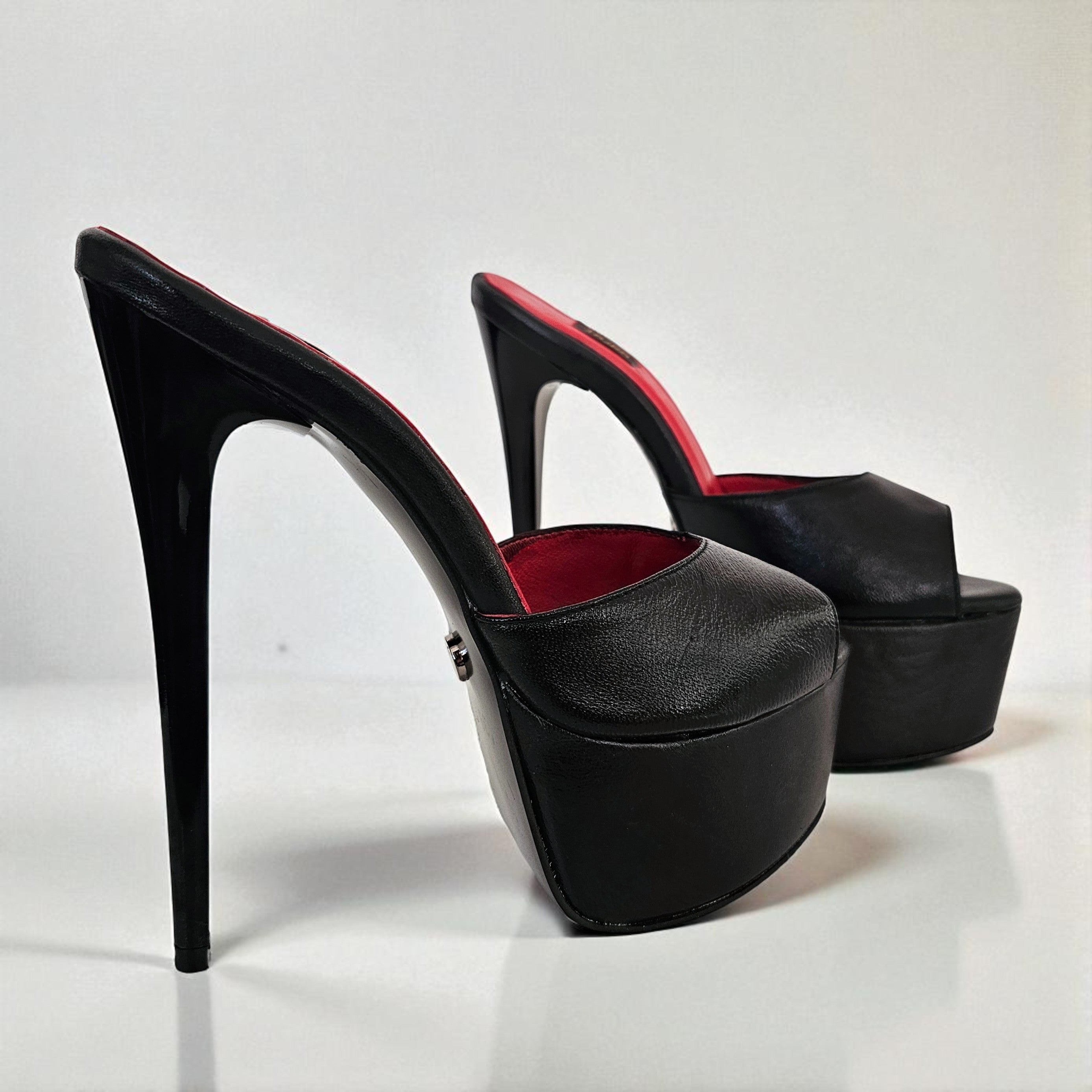 Black high-heeled platform shoes with red interior on a white background