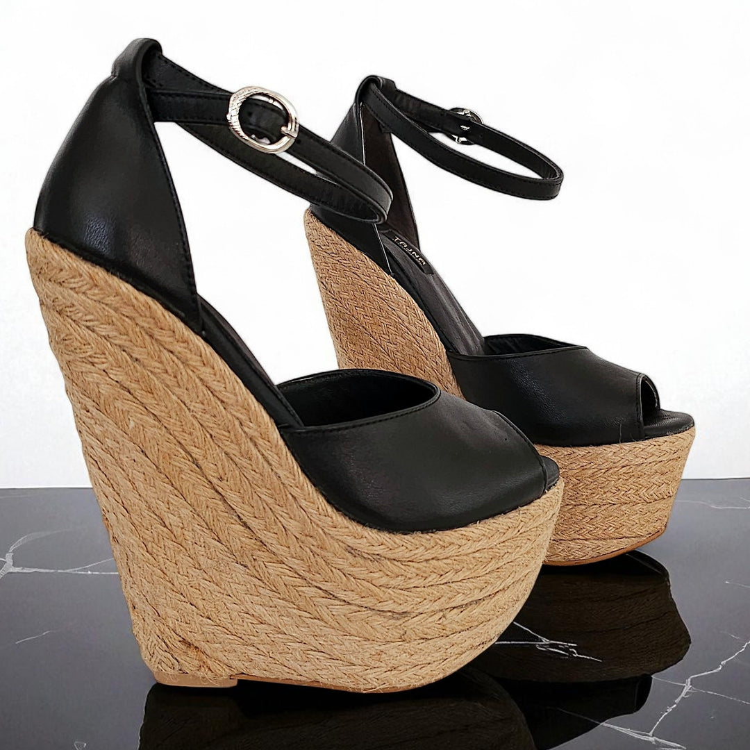 Black wedge sandals with woven wedge on a reflective surface