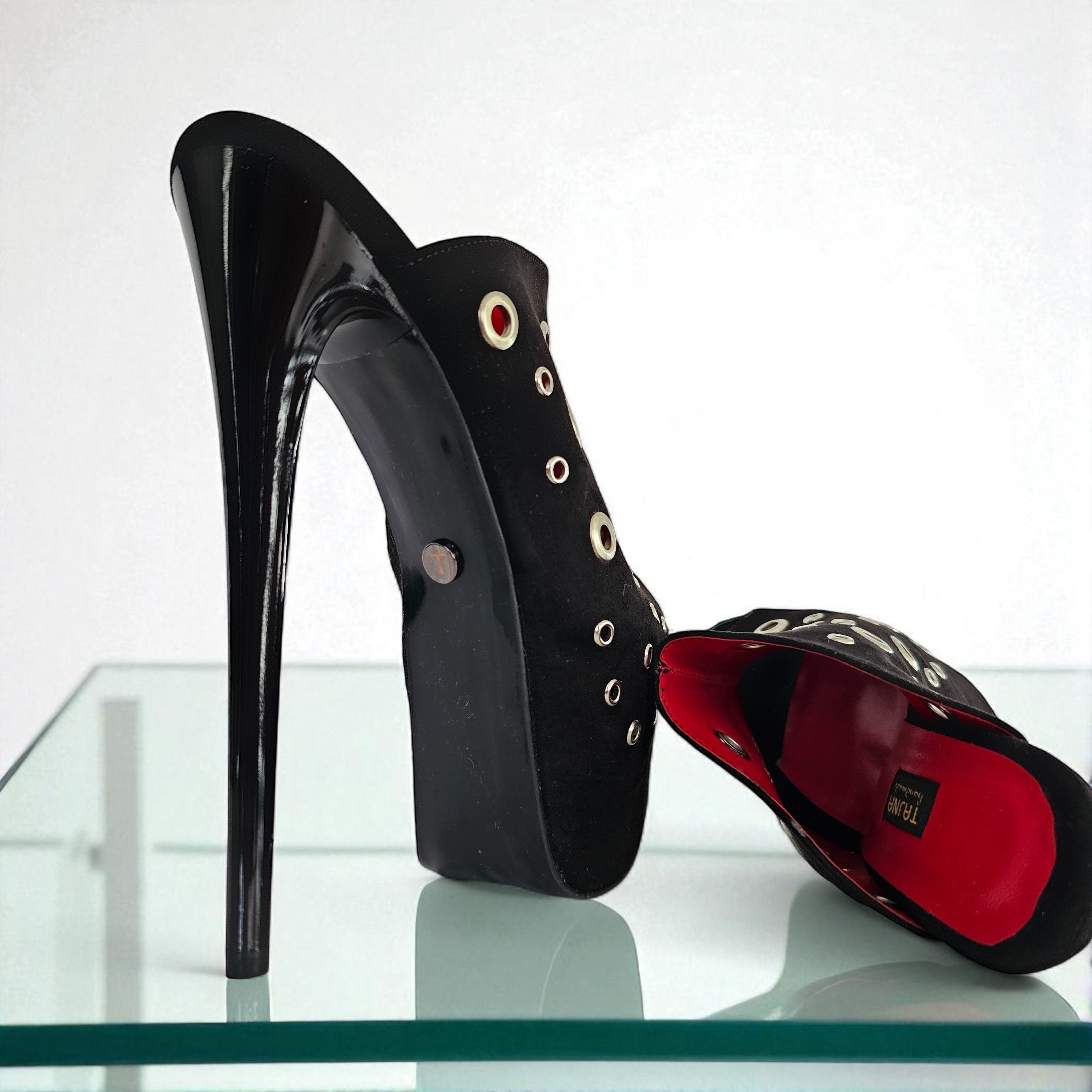 Black high-heeled shoe with red interior on a clear surface