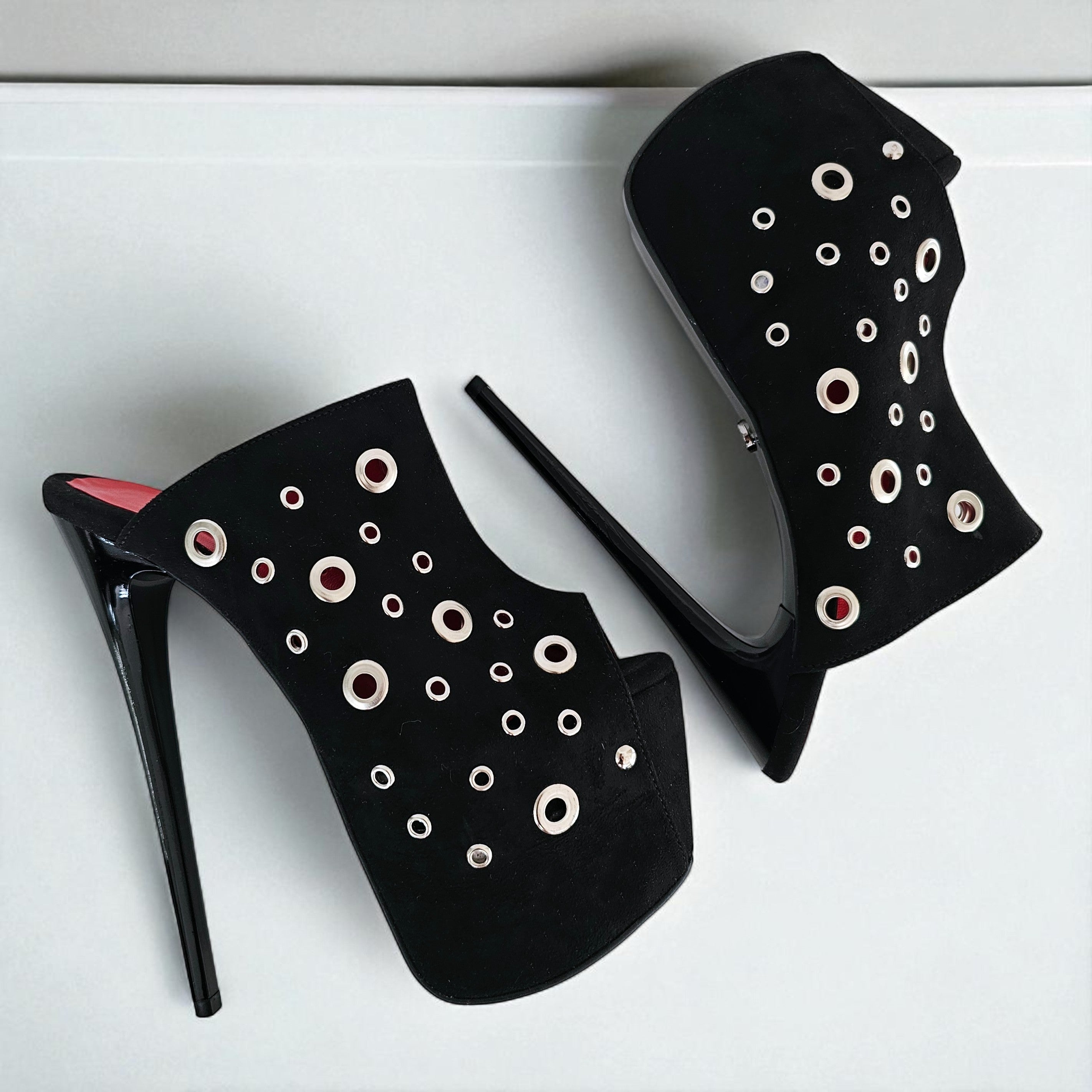 Black high-heeled shoes with circular cutouts on a white background