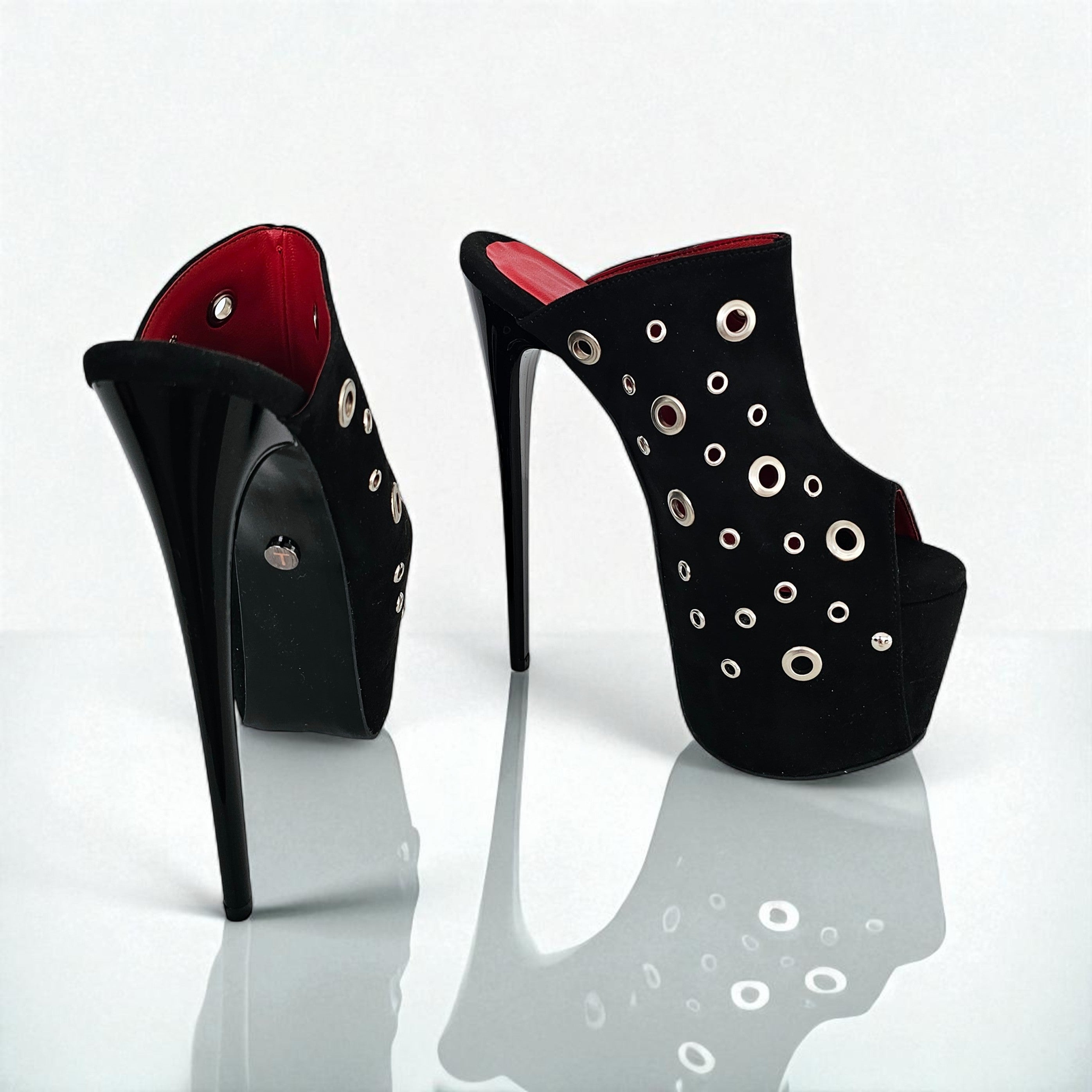 Black high-heeled shoes with red interior and decorative eyelets on a white background