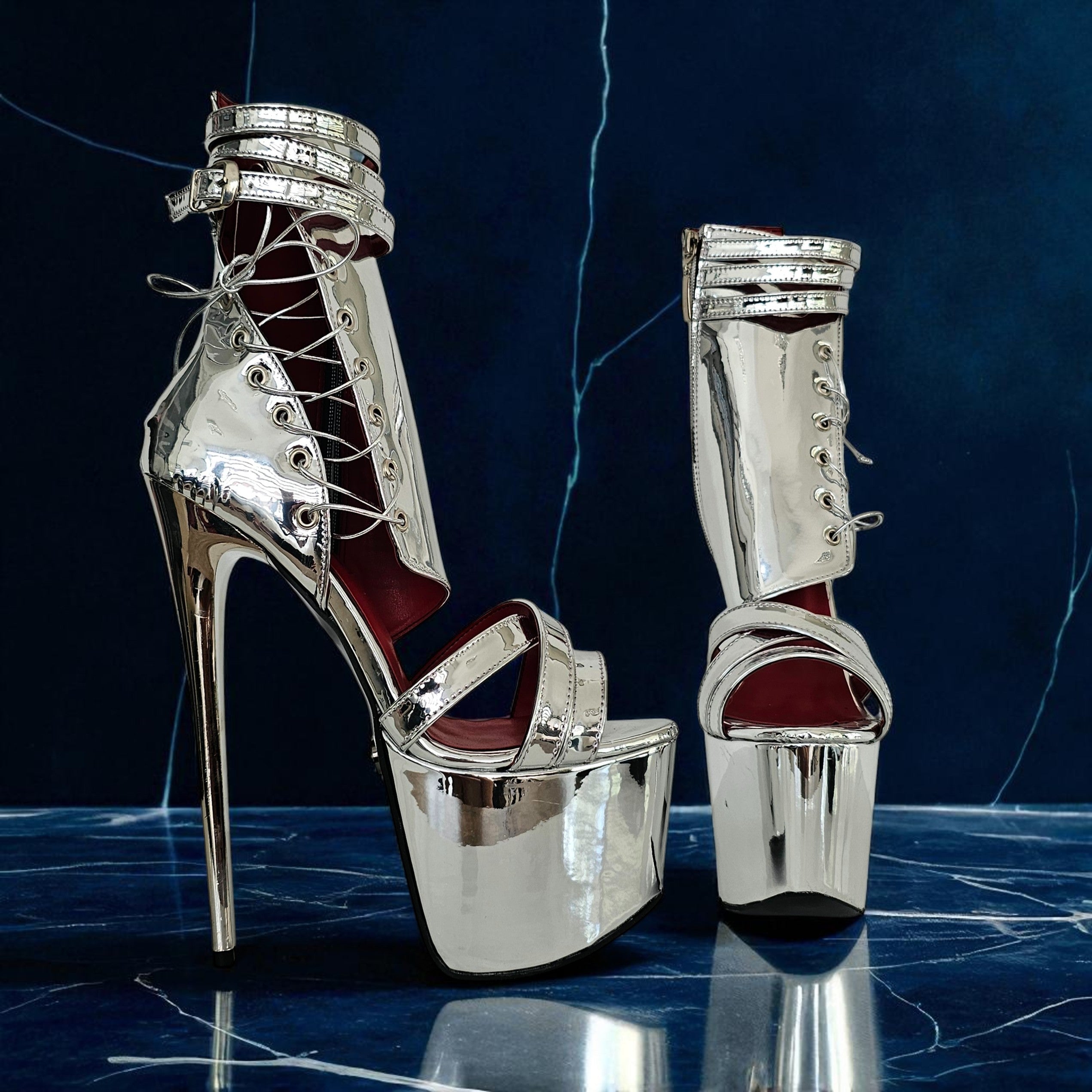 Silver high-heeled platform shoes on a dark blue marble surface