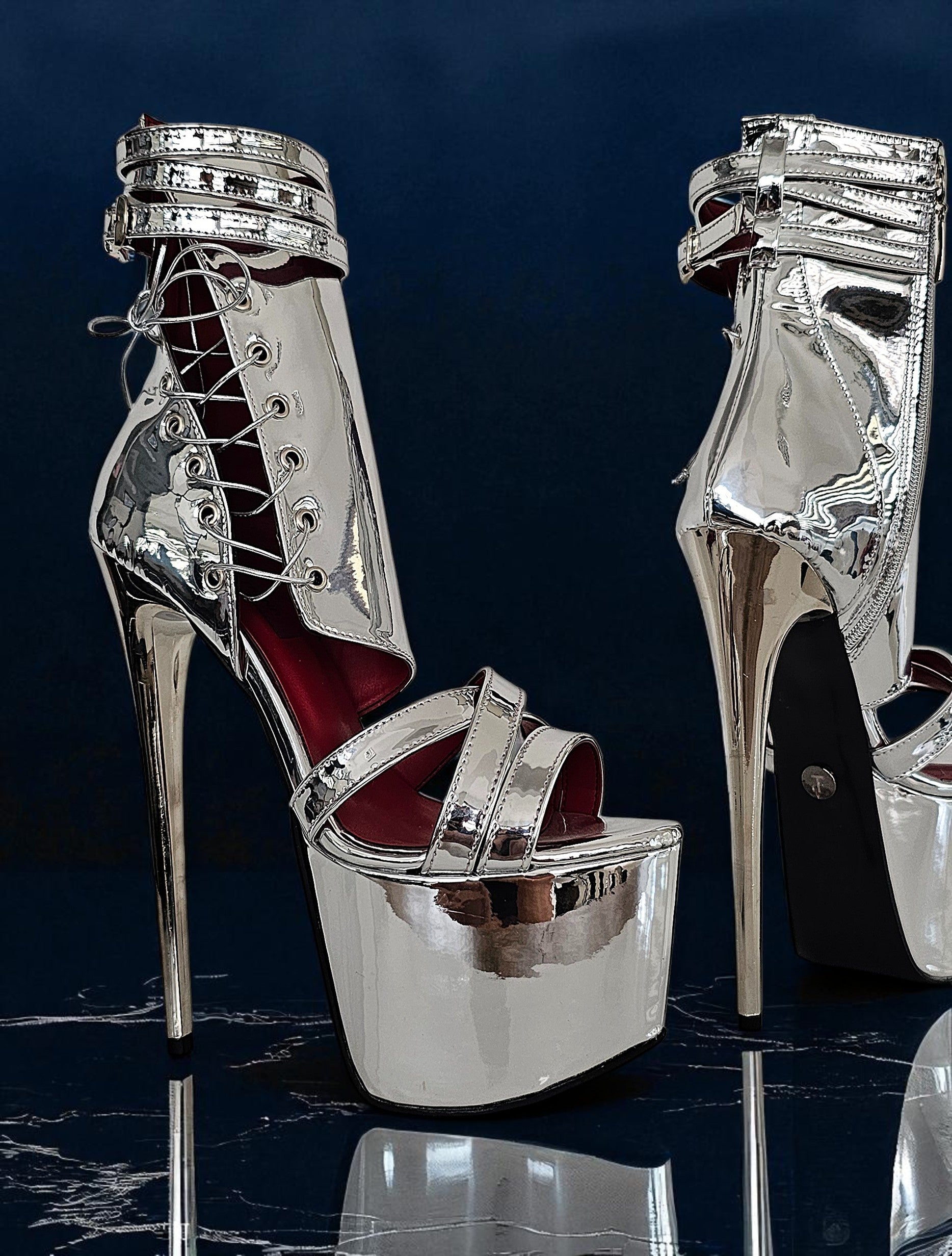 Silver high-heeled shoes with platform on a dark reflective surface