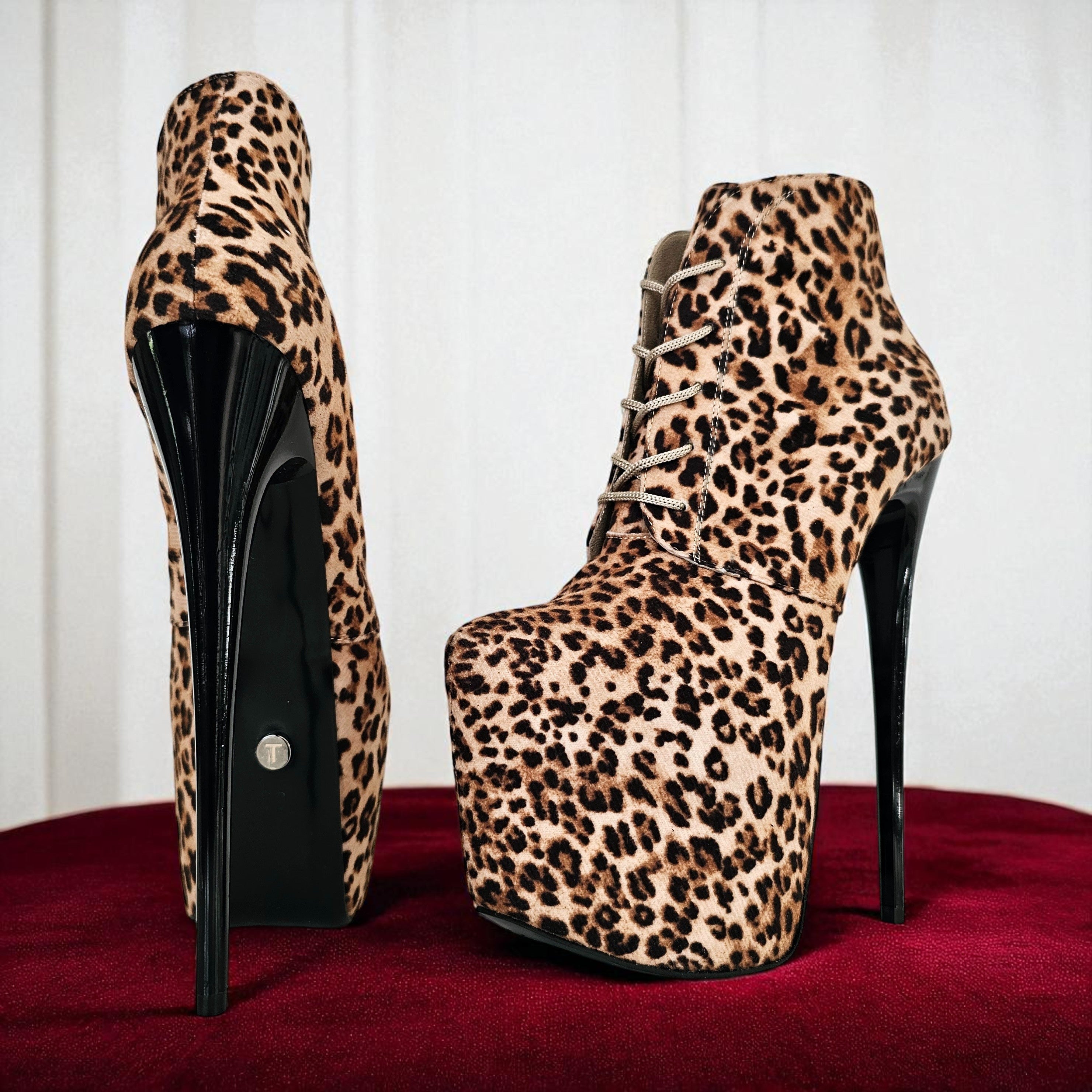 Leopard print high-heeled platform boots on a red surface with a white background