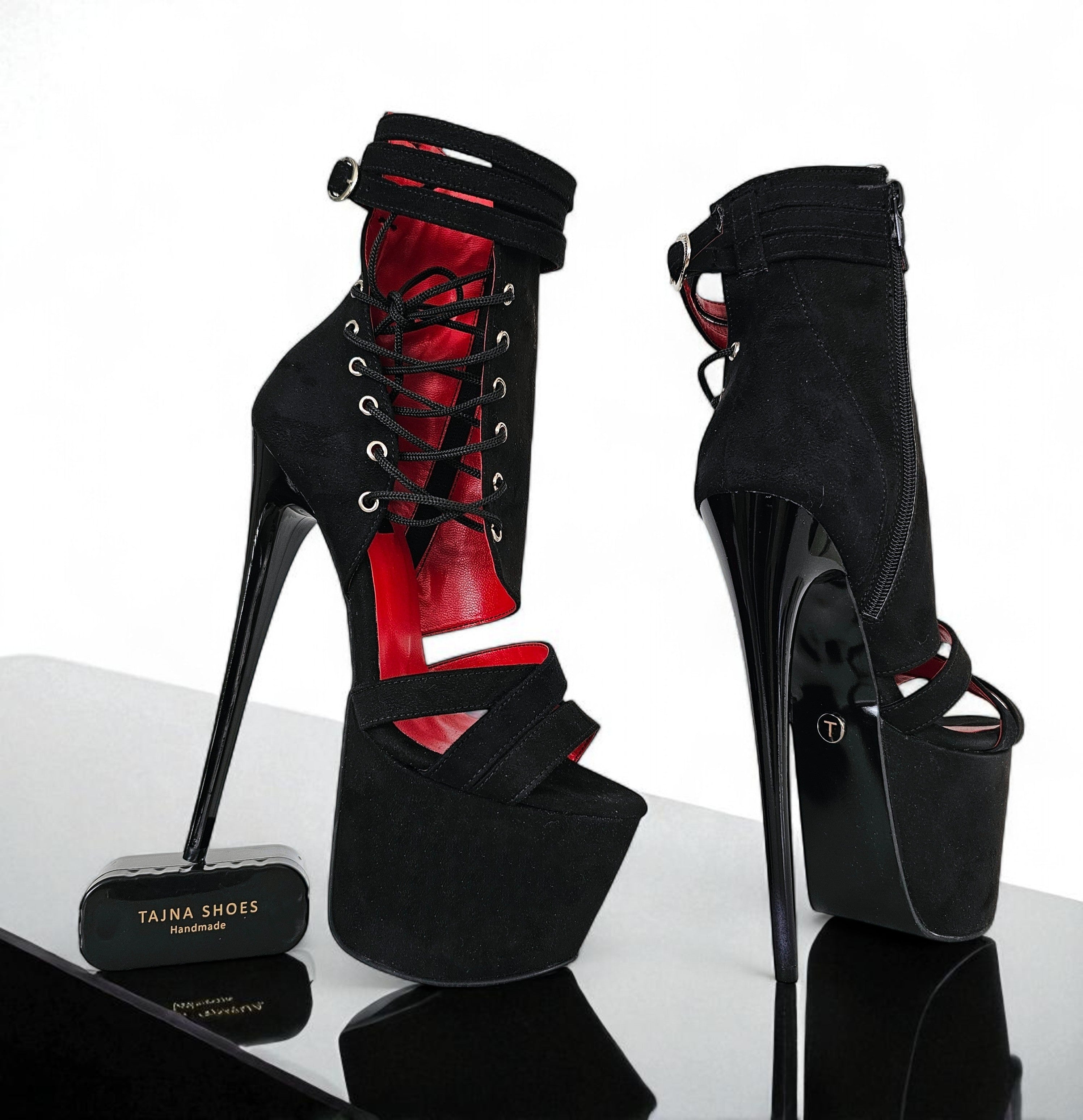 Black high-heeled shoes with red interior on a reflective surface, branded 'Taina Shoes'.